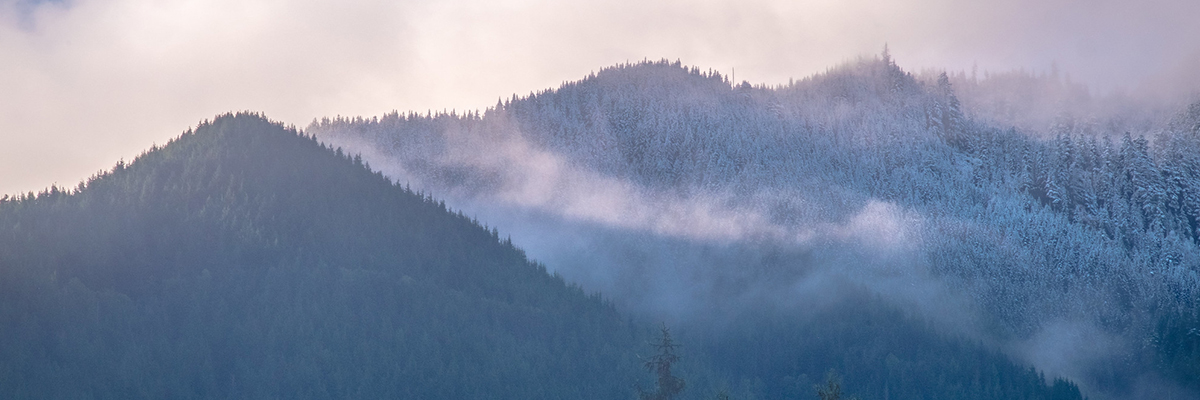 A photo of two foothills, one covered with snow
