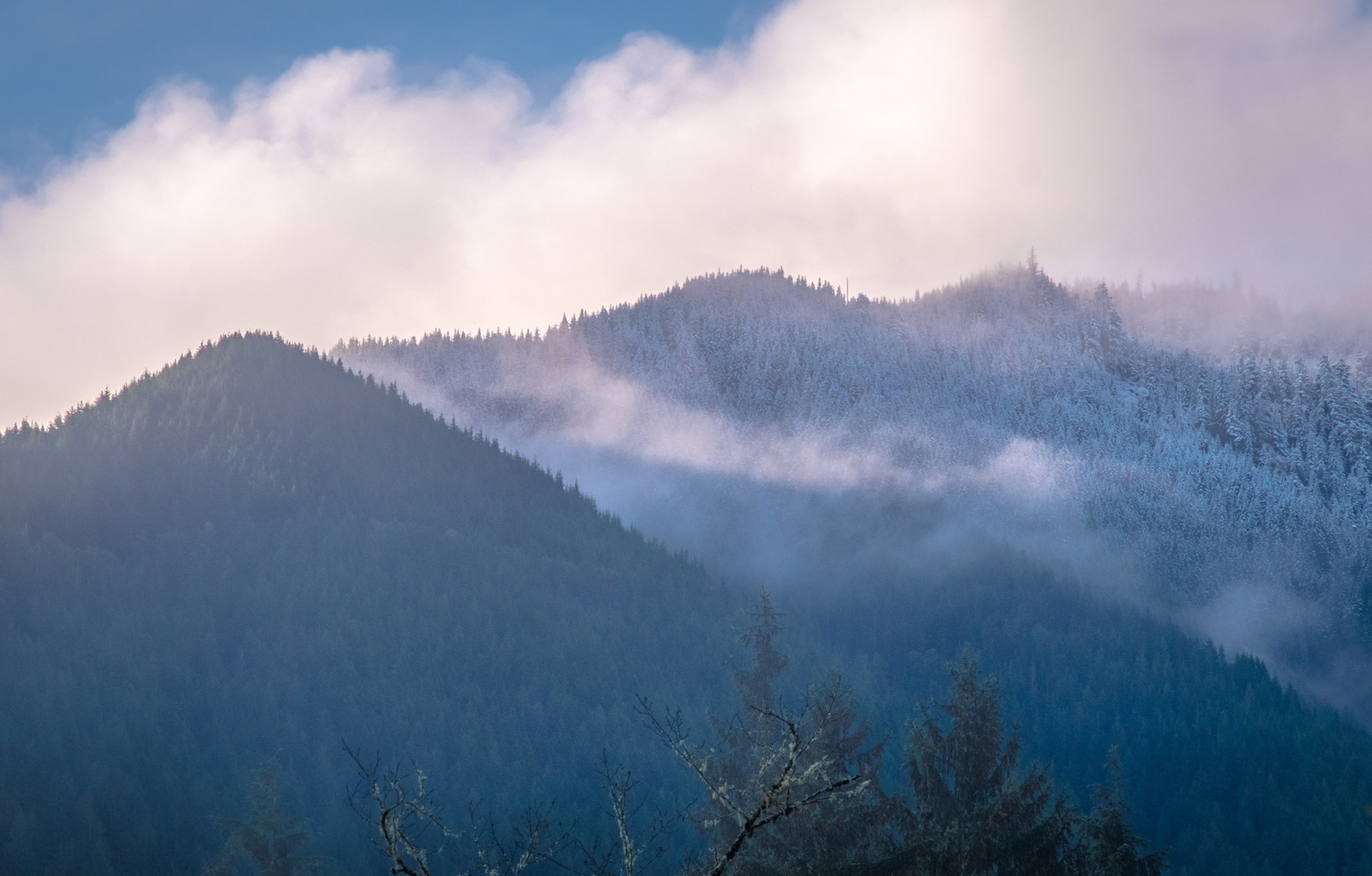 A photo of two foothills, one covered with snow