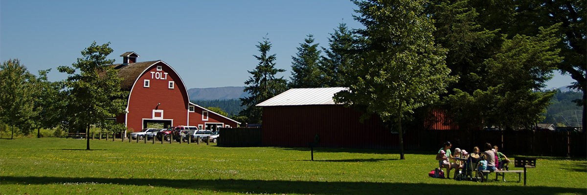 A family picnics near the red barn at Tolt Macdonald Park