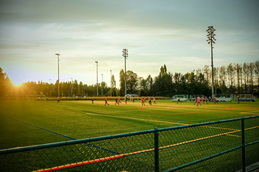 Soccer players in red uniforms out on the fields in the setting sun