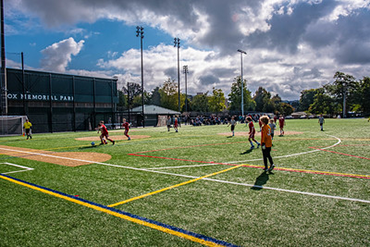Kids play on a turf soccer field next to Mel Olson Stadium