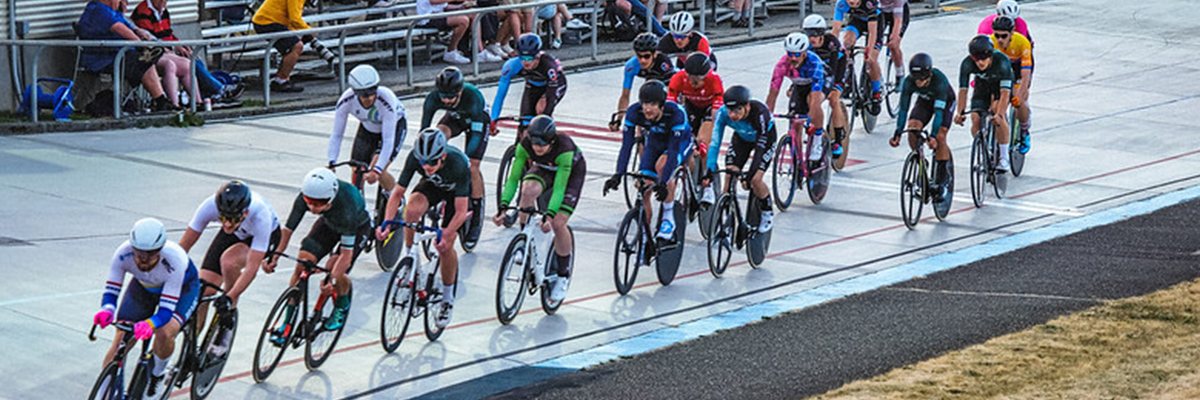 A group of bicyclists racing around a track with people watching from bleachers