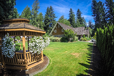 A gazebo with hanging white flowers and the Jim Ellis Community Center