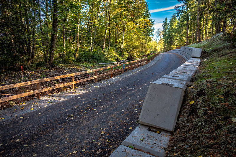 A section of the Foothills Trail with a retaining wall in the foreground and a wooden fence along the opposite side
