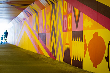 A person and their child ride through the Wayne Tunnel on the Burke-Gilman Trail