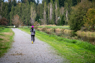 A runner jogs down the gravel path along the river