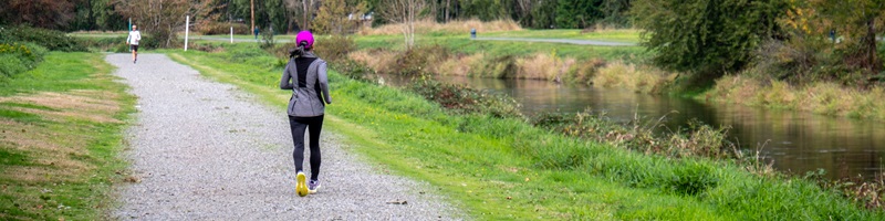 A person in a pink hat running on a gravel trail alongside the Sammamish River