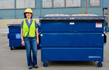 Solid waste worker standing in front of a 4-yard garbage dumpster