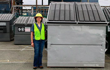 Solid waste worker standing in front of a 8-yard garbage dumpster