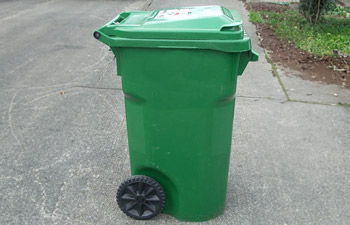 Image of a green 96-gallon garbage tote in a driveway