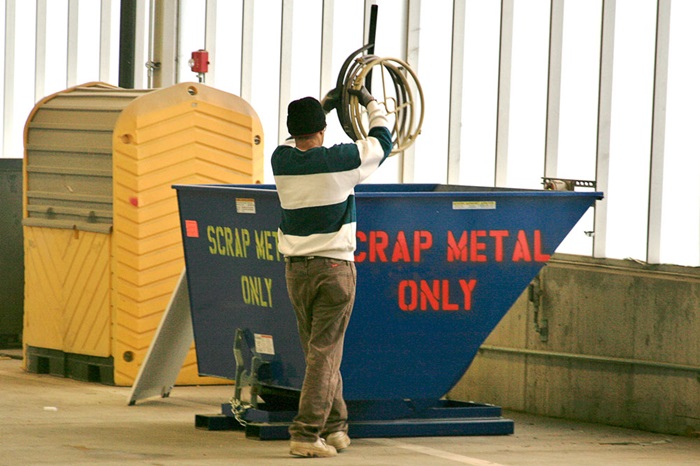 A customer adds scrap metal to a bin at a King County Recycling and Transfer Station