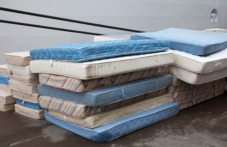 Image showing several neatly-stacked piles of used mattresses