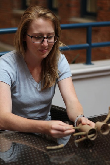 Girl making reindeer table decoration out of twigs and toilet paper rolls.