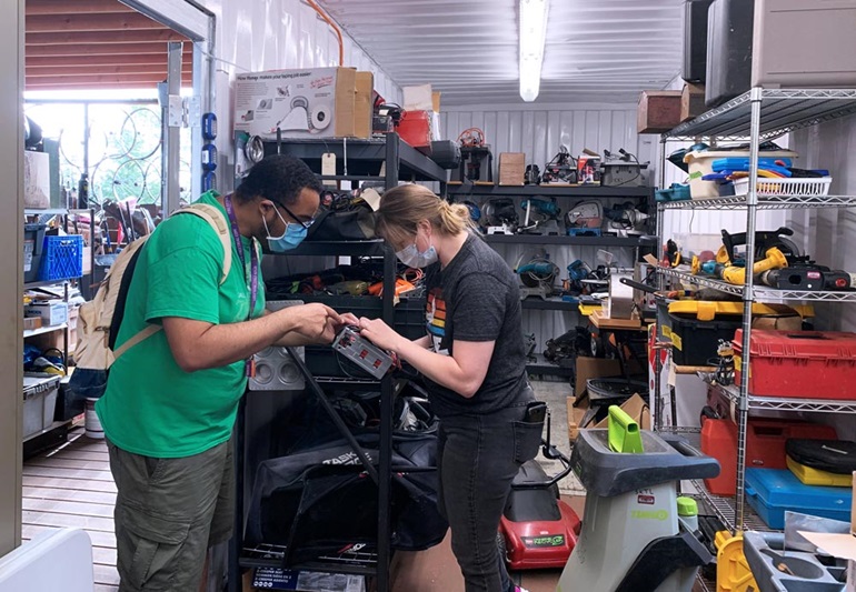 image of an employee and a customer examining a tool in a tool-lending facility