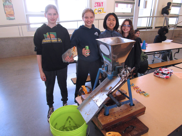 Students at Environmental & Adventure School use a grinder to break down food waste before putting it in the on-site compost tumbler