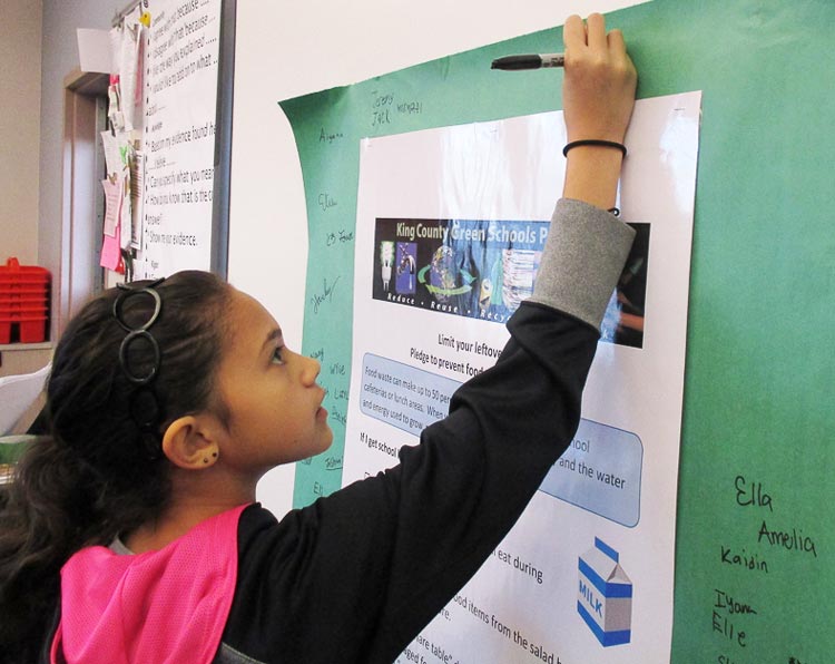 Student signs a pledge to reduce food waste at school