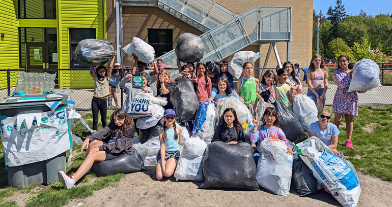 An image of several students from Margaret Mead Elementary School holding large bags stuffed with plastic film, which they have collected for recycling