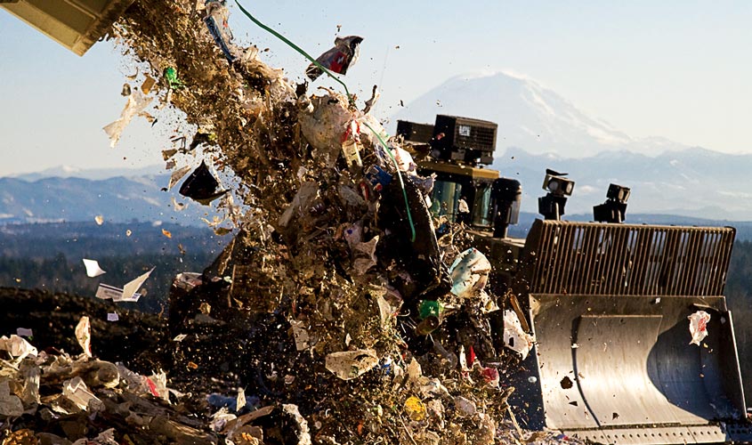 Image of garbage being dumped in front of a bulldozer at Cedar Hills Regional Landfill in King County, with Mount Rainier in the background