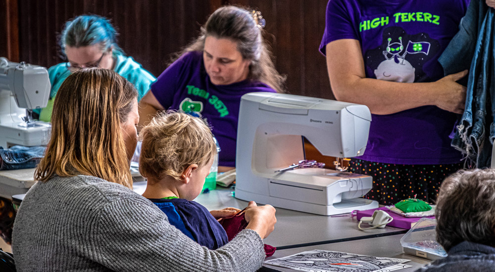 Image of three Fixers working at a Repair Event - all three using sewing machines to repair clothing brought to the event by King County residents