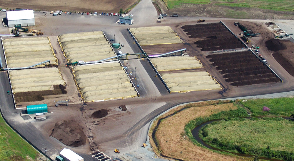 An overhead or aerial photo of the Cedar Grove Composting facility with rows of compost, a conveyor belt, and a tractor.