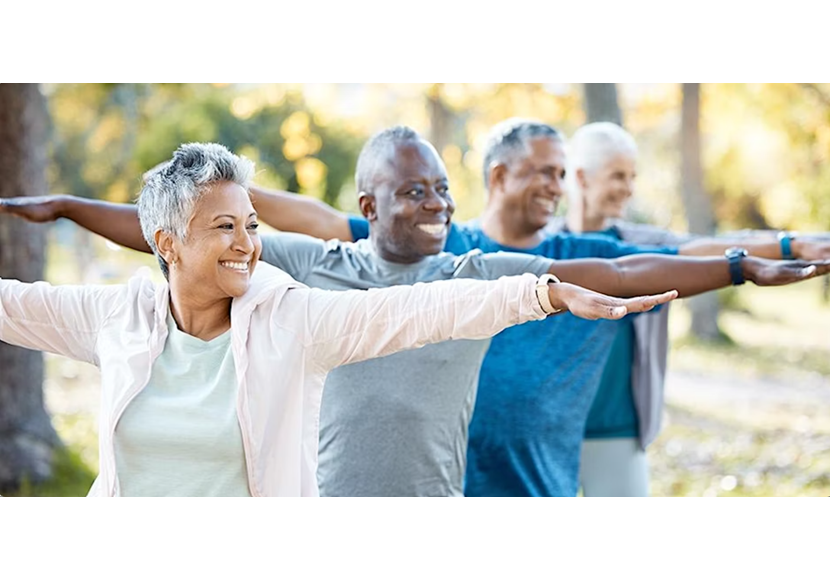 Four senior individuals stretch and smile while standing in a row