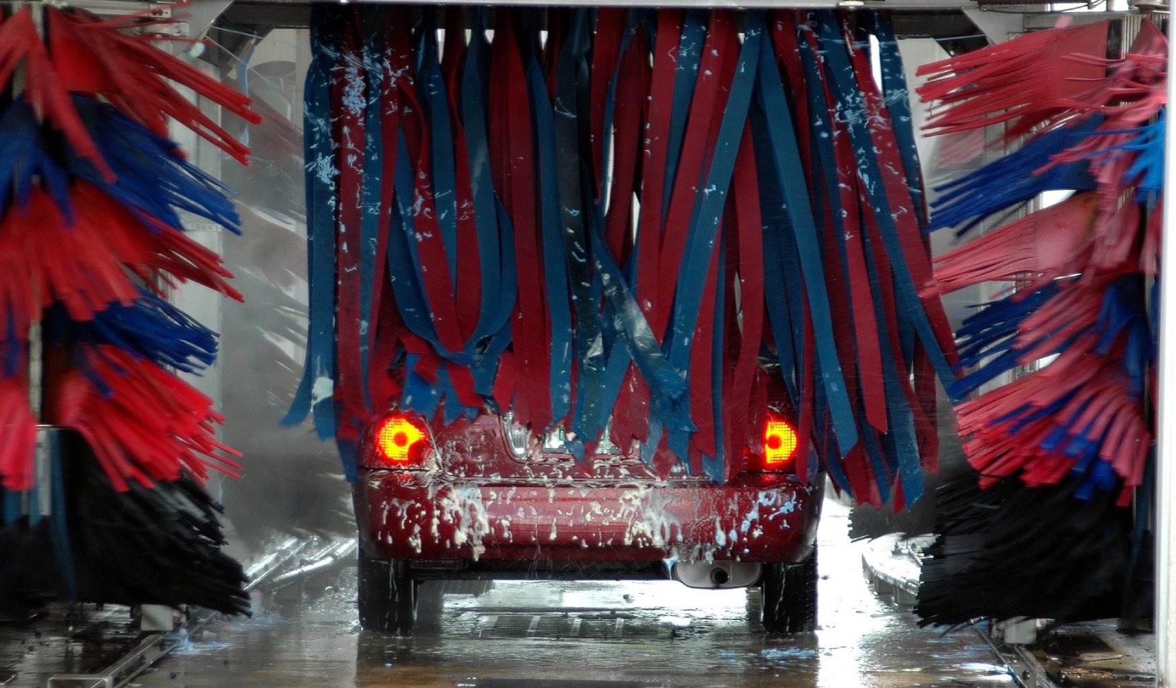 Red car driving through commercial car wash