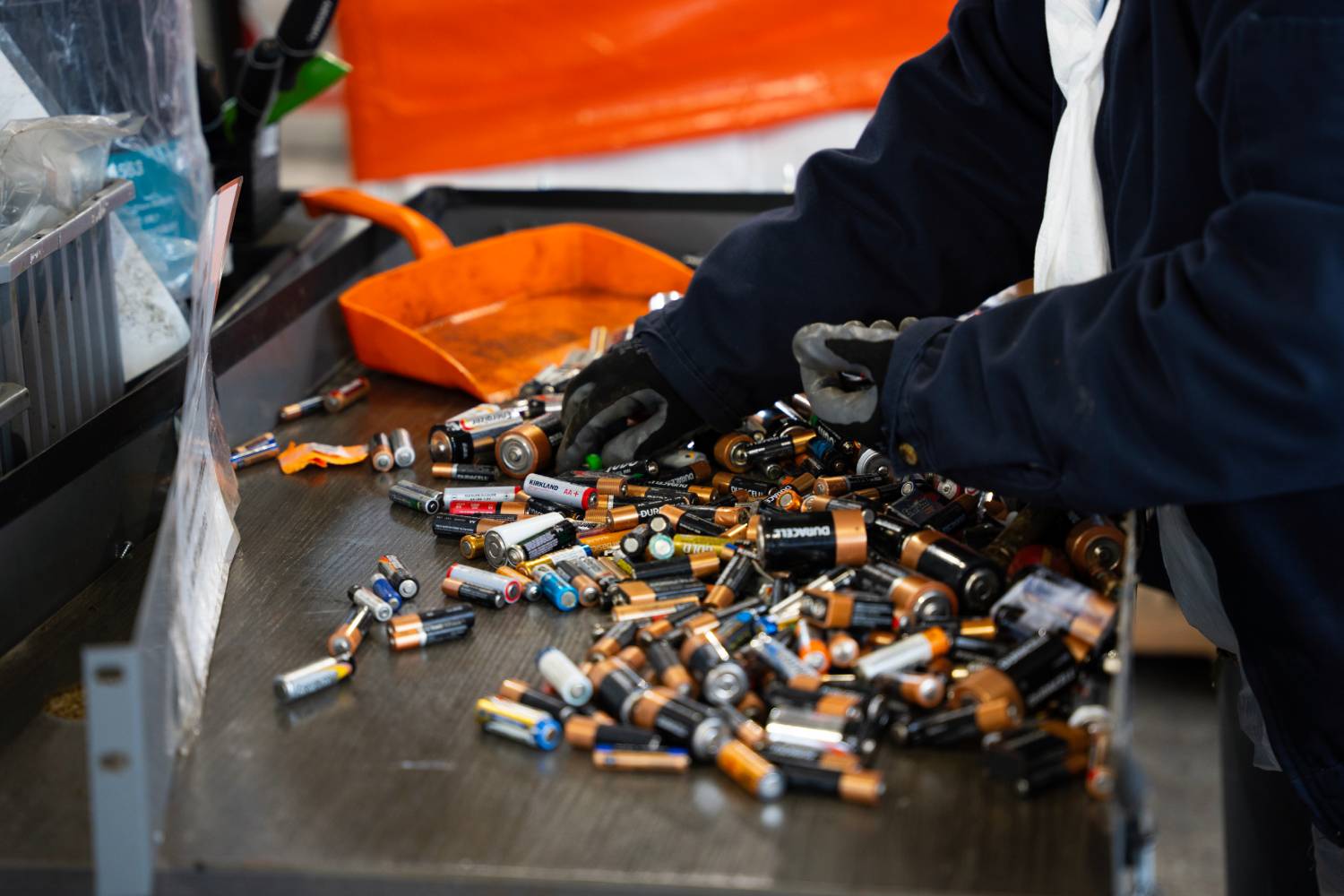 Two hands sorting through a pile of batteries