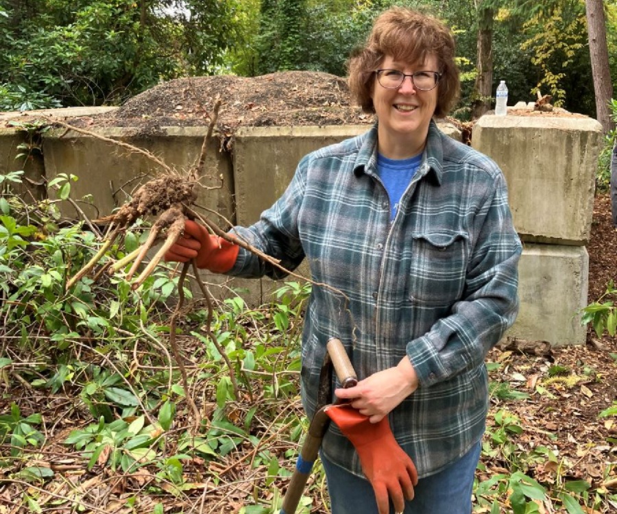 An image of Alice Chapman, Haz Waste Program staff member, holding tree branches and work gear at a tree planting event