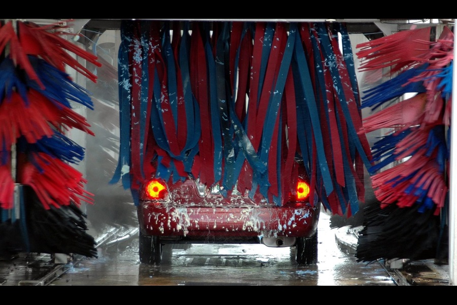 A father and daughter washing a black car with soapy sponges