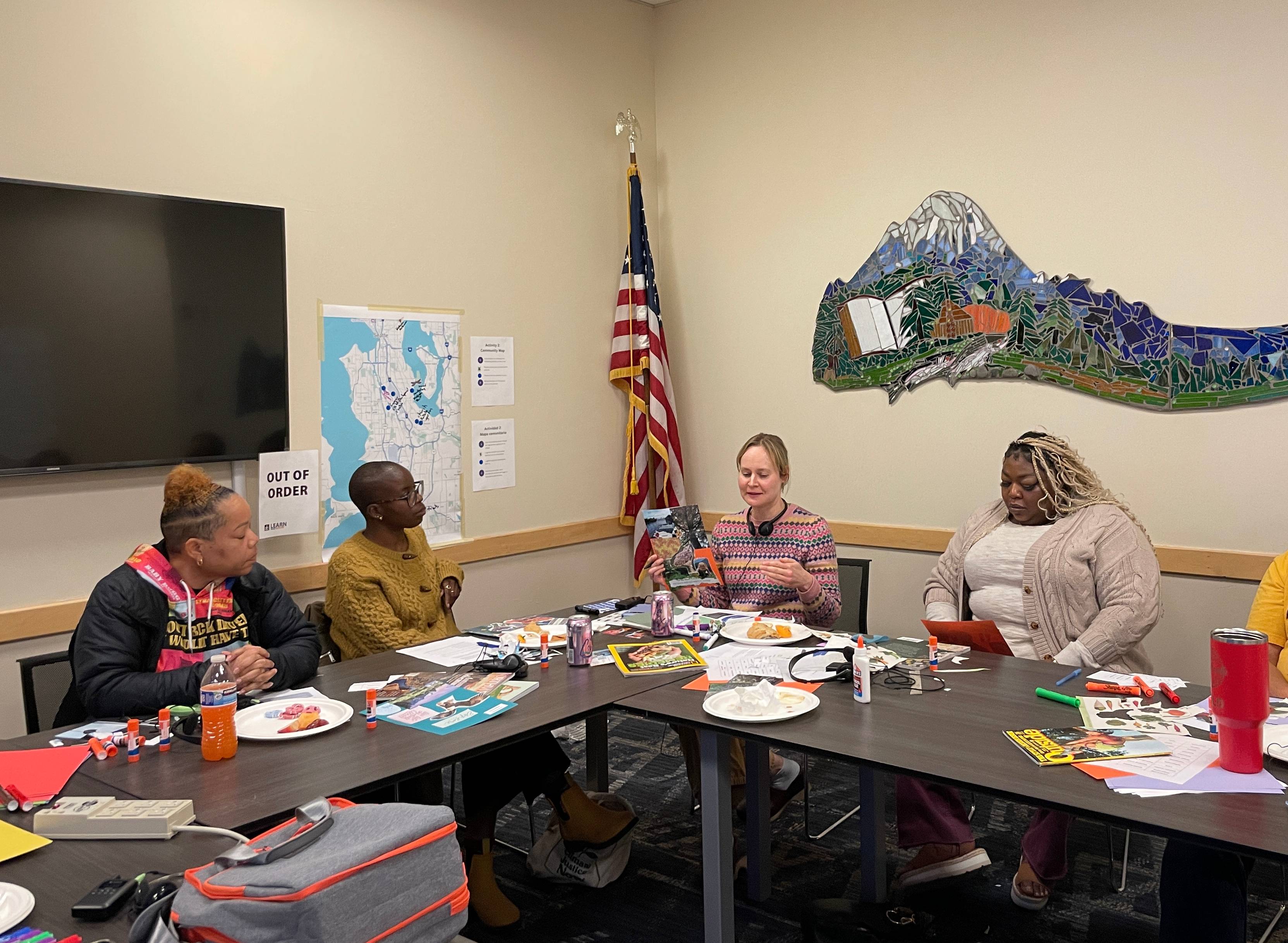 Four community members sit around a table in discussion. 