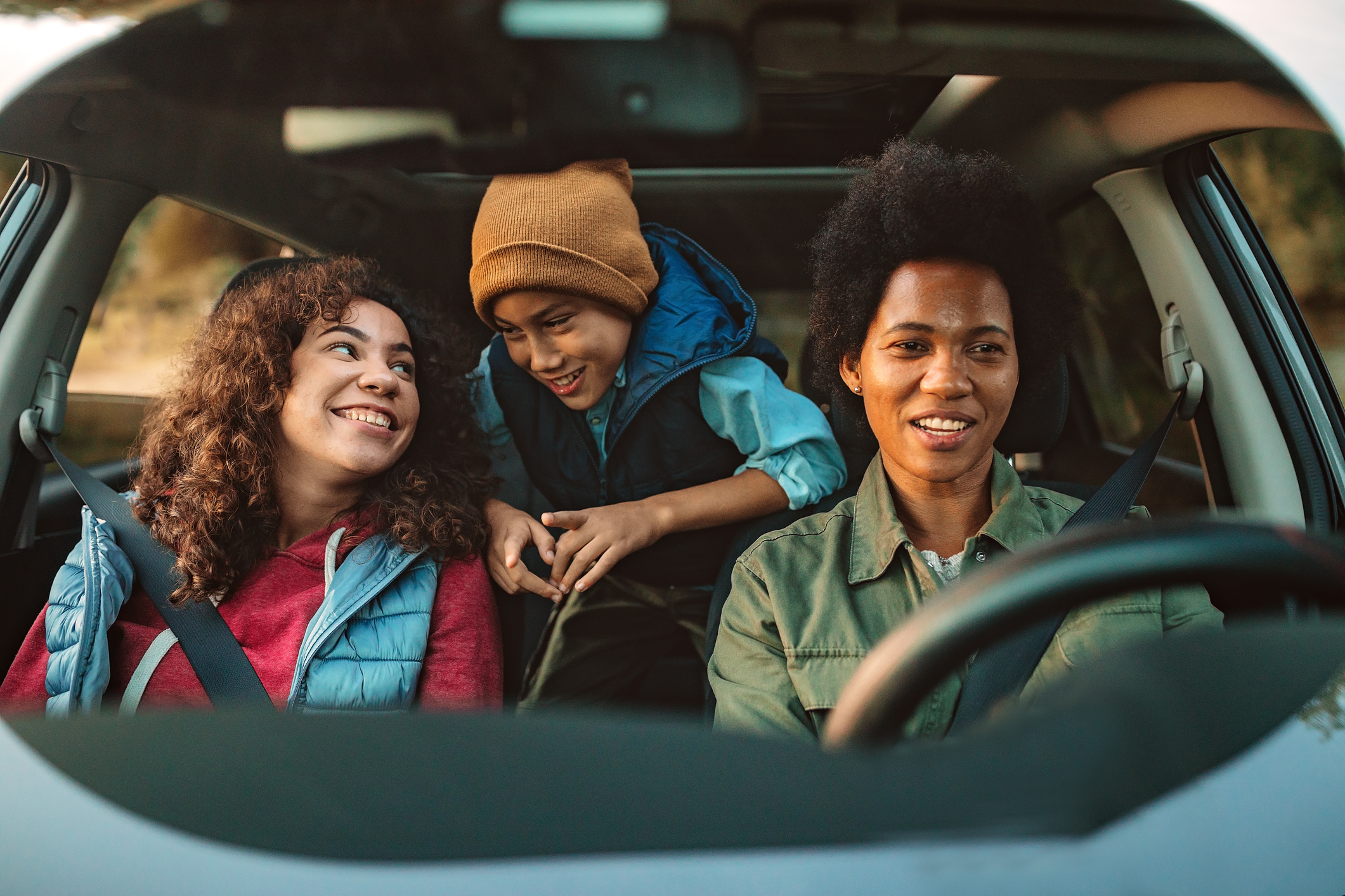 Three people in winter clothing ride in a car.