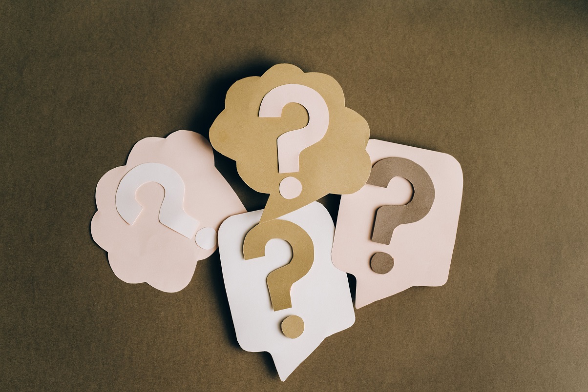 Paper cutouts of pink, white, and beige question marks.