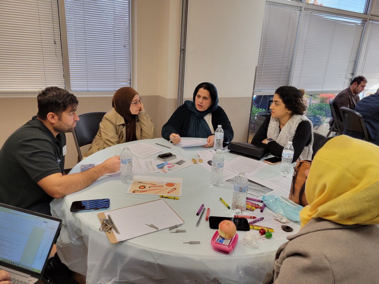 Afghan community members sit at table in discussion