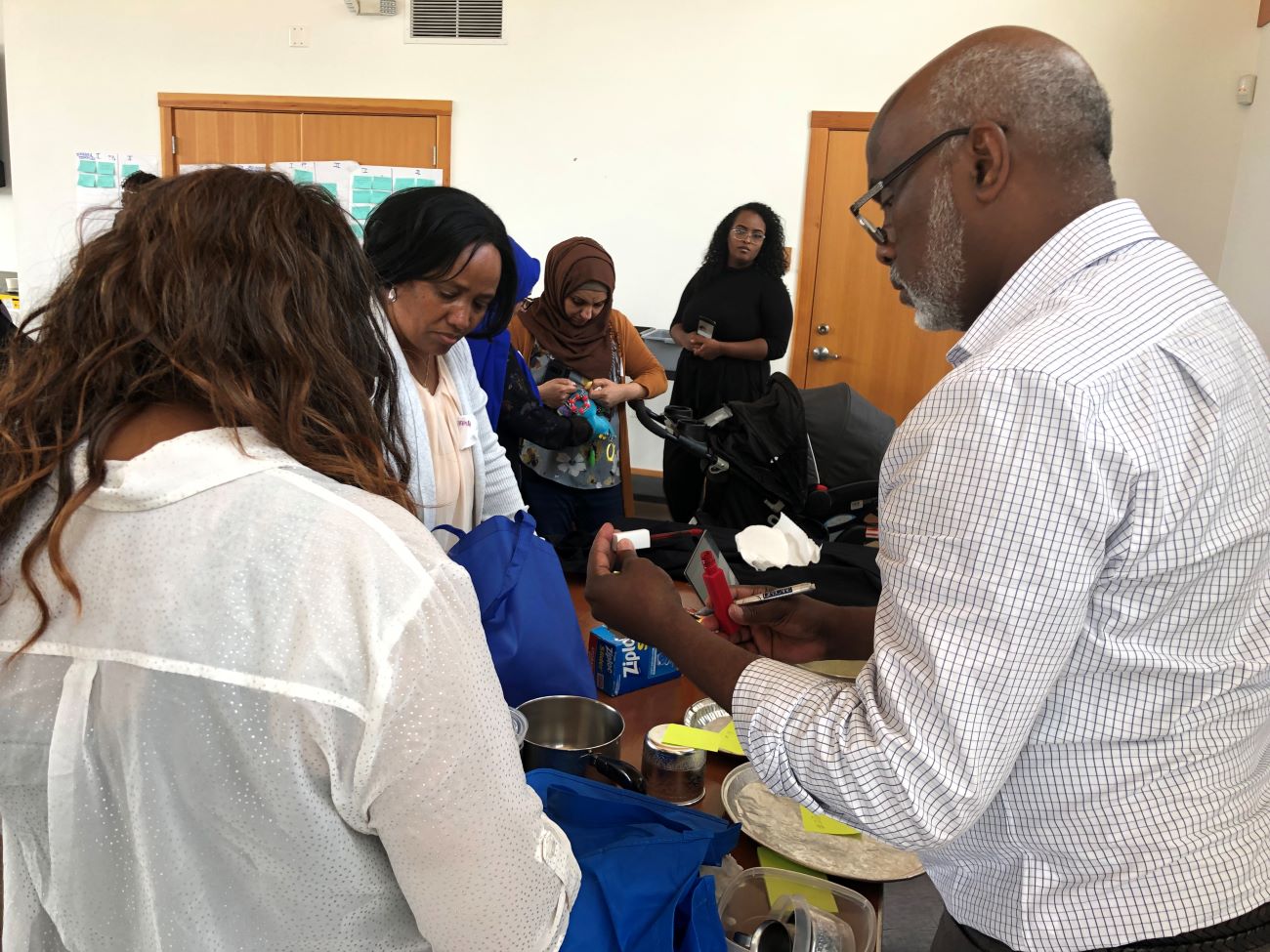 A Black man helps four Black women identify hazardous products at a lead product testing event