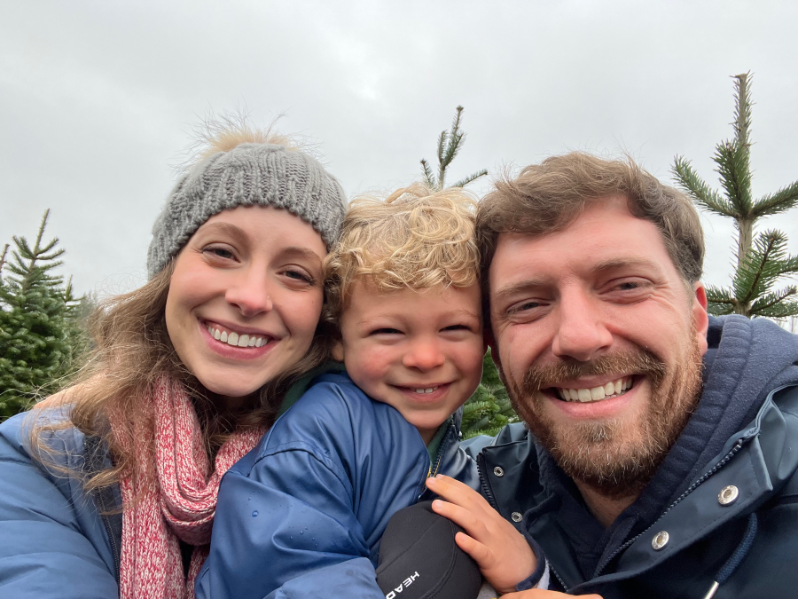 An image of Haz Waste Program staff Myles Perkins and his family in front of evergreen trees and gray, cloudy sky