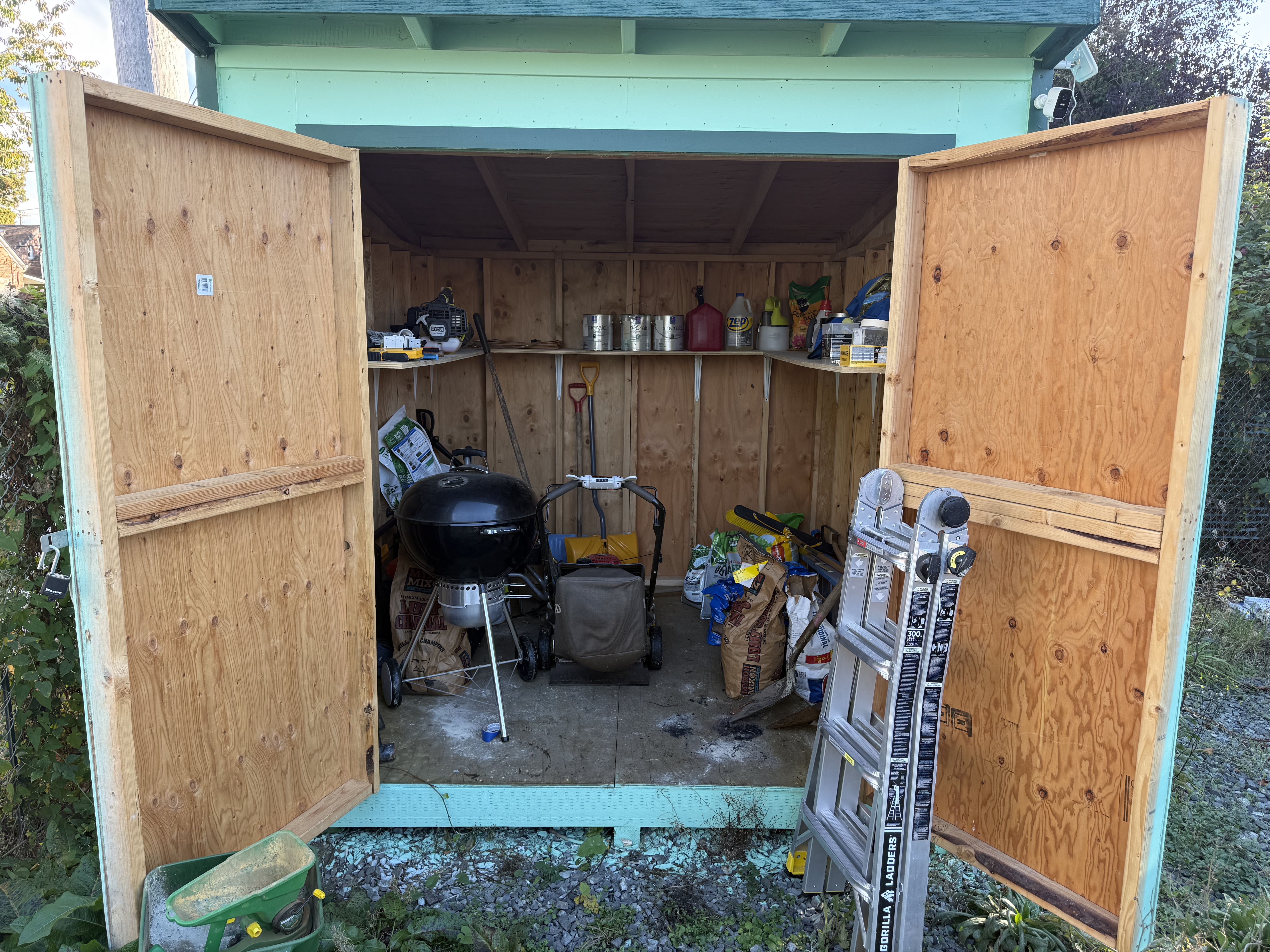 Turquoise shed containing tools, soil, and hazardous waste. 