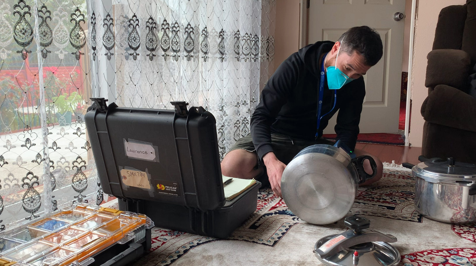 Man with mask on testing cooking pot for lead