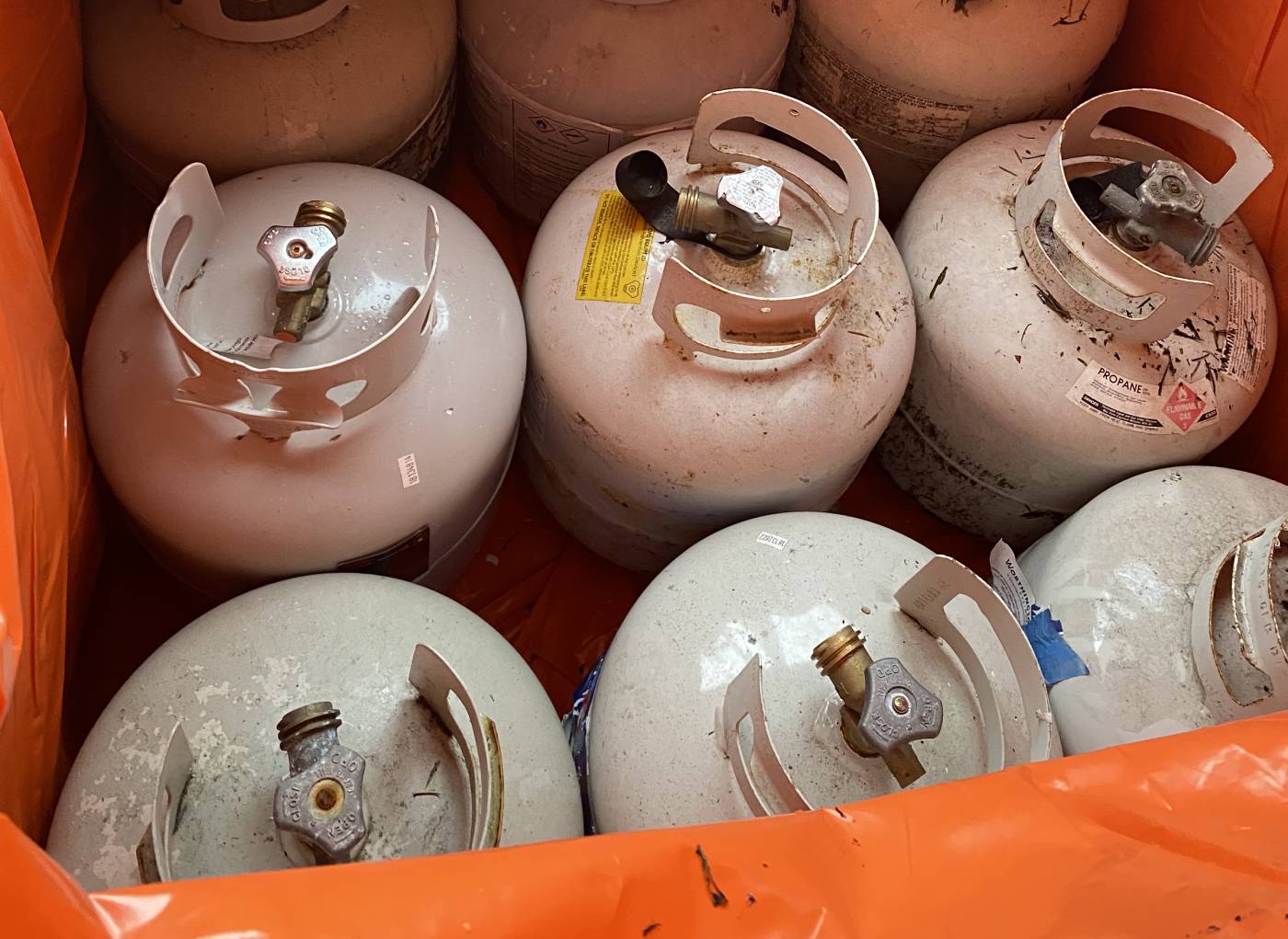 Six propane tanks in orange crate. 
