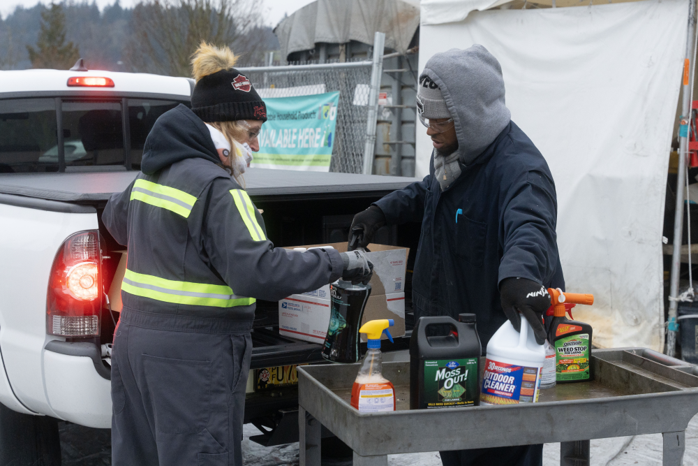 Two workers sorting hazardous waste out of truck
