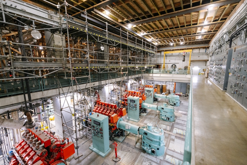Large sewage pumps, painted in teal and orange, inside of a large industrial room inside of the West Point Treatment Plant.
