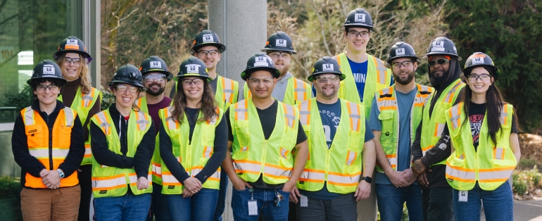 A group of operators in training with personal protective gear: yellow reflective vests, hard hats and eye protection. 