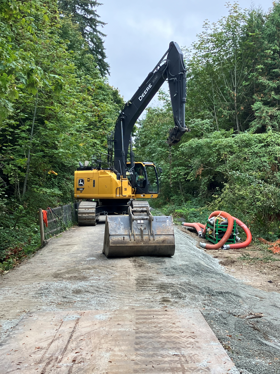 Excavator and construction equipment on the closed Cross Kirkland Corridor trail during repairs to a culvert near the ESI 14 sewer pipe. Crews are stabilizing the area and preparing for temporary sewer flow diversion as part of the repair work.