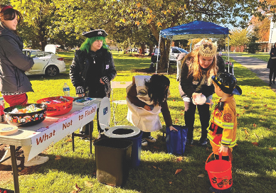 A woman, dressed as a princess, talks to a young boy in a firefighter costume.