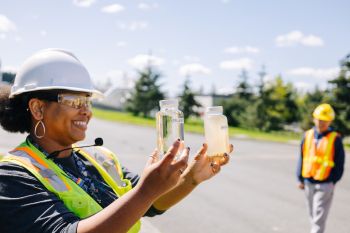 King County Wastewater Treatment Educator in safety gear holds water samples.