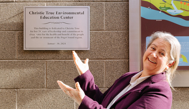 Christie True, retired director of King County Department of Natural Resources and Parks, stands next to the facility sign named in her honor.