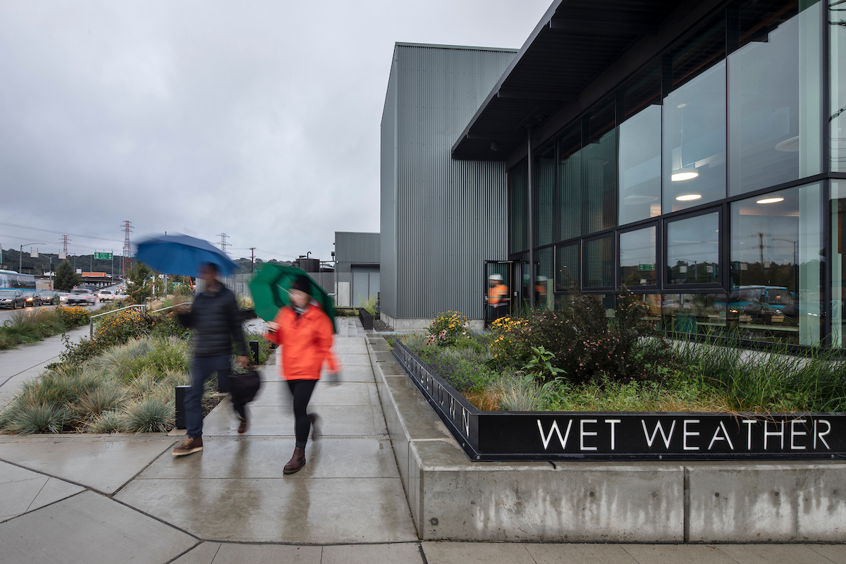 Two people on the sidewalk next to the entrance to the Georgetown Wet Weather Treatment station.