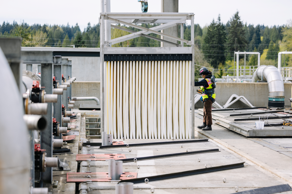A utility worker uses a crane to move the new membrane cassette into an open space in the train.