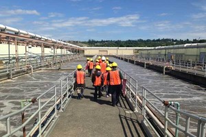 A group of people in orange vests and hard hats tour the South Treatment Plant