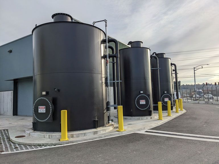 Three large black cylindric cisterns collect rainwater at the facility.