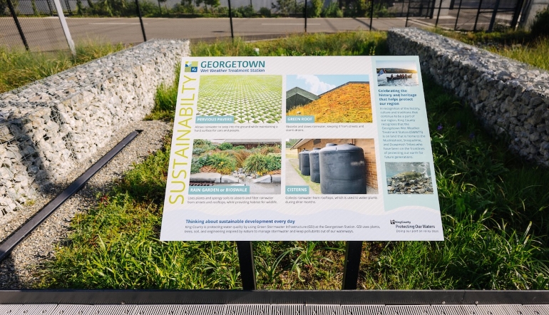 An educational board on the topic of Sustainability is located in a rain garden, located at the facility.